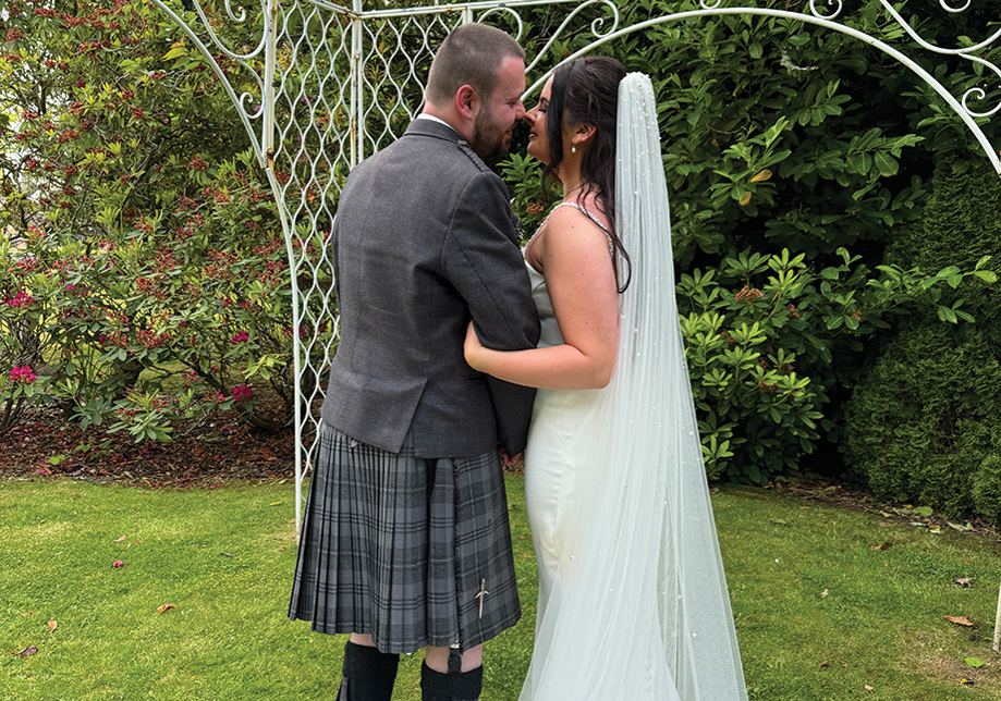 Bride and groom embrace under white archway